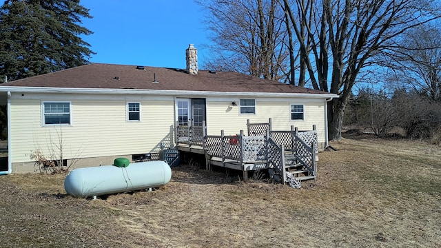 rear view of property with a wooden deck, a chimney, and a shingled roof