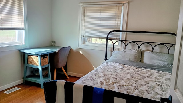 bedroom featuring visible vents, baseboards, and wood finished floors