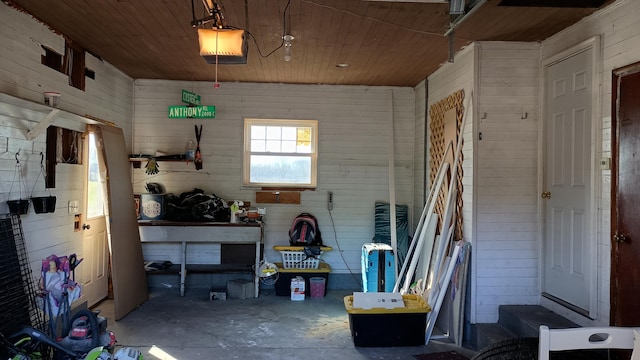 garage featuring a porch, wooden walls, wood ceiling, and a garage door opener