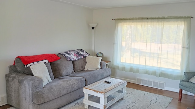 living area with visible vents, a healthy amount of sunlight, baseboards, and wood finished floors