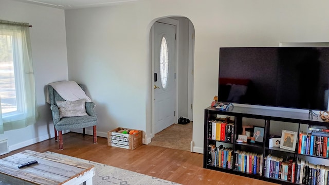 living area featuring arched walkways, baseboards, and wood finished floors