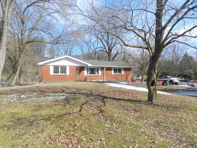 view of front of house featuring brick siding, a front lawn, and fence