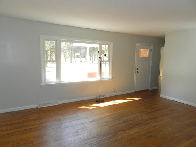 interior space featuring dark wood-style floors, baseboards, visible vents, and a wealth of natural light