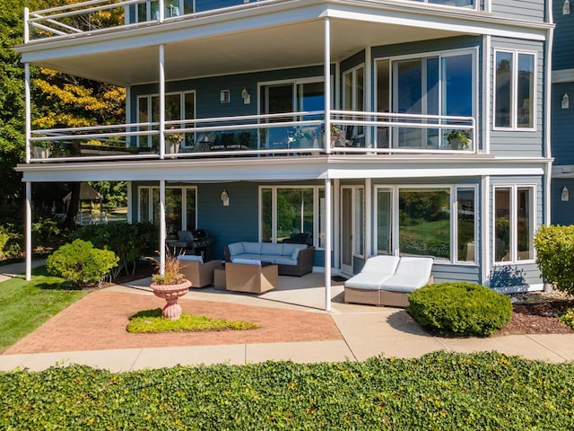 rear view of house with an outdoor living space, a balcony, and a patio area