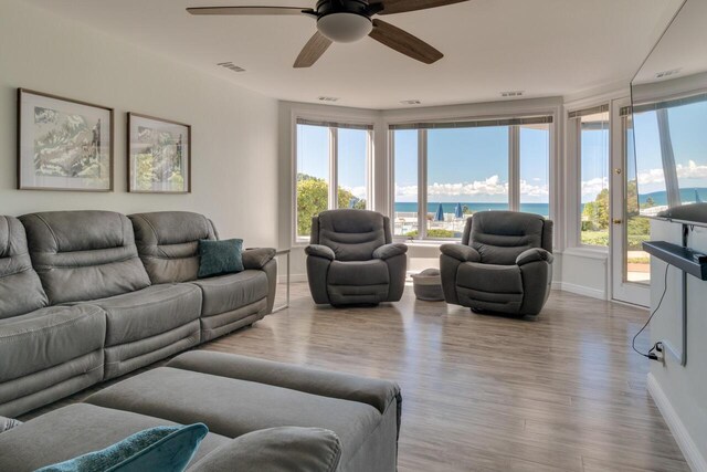 living area featuring wood finished floors, visible vents, a water view, and baseboards