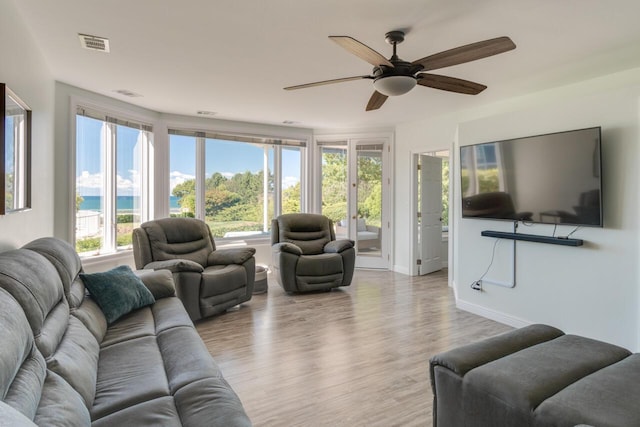 living area featuring visible vents, baseboards, ceiling fan, and wood finished floors