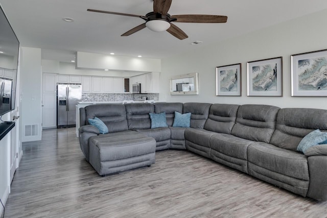 living room with a ceiling fan, recessed lighting, light wood-style floors, and visible vents