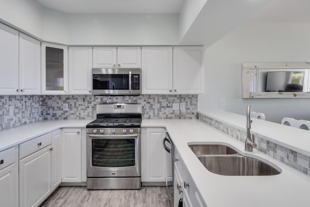 kitchen featuring a sink, stainless steel appliances, light countertops, white cabinets, and tasteful backsplash