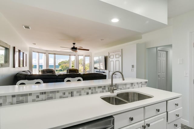 kitchen featuring open floor plan, dishwasher, light countertops, white cabinets, and a sink