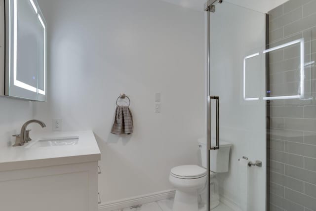 bathroom with vanity, a shower stall, toilet, and baseboards