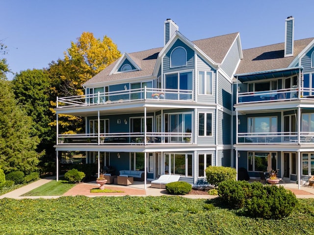 rear view of property with outdoor lounge area, a patio, a yard, and a chimney