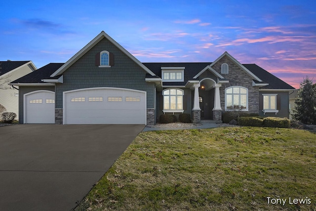 view of front of property featuring stone siding, a front lawn, concrete driveway, and a garage