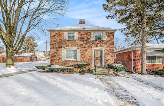 view of front of house with a chimney, fence, and brick siding