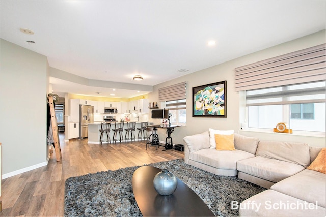 living area with recessed lighting, visible vents, light wood-style flooring, and baseboards