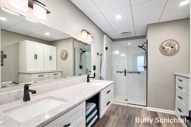 full bathroom with a sink, double vanity, wood finished floors, and a shower stall