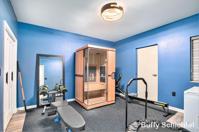 exercise room featuring baseboards and a textured ceiling