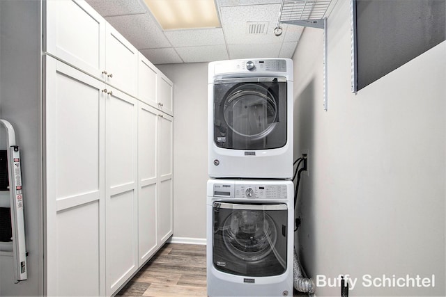 washroom featuring light wood-type flooring, cabinet space, and stacked washer / dryer