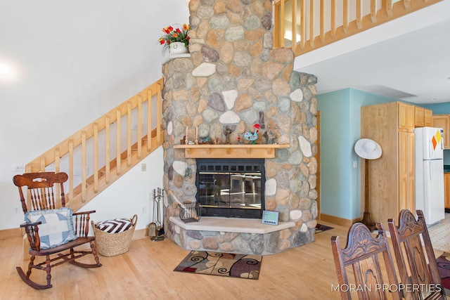 living room with wood finished floors, baseboards, a fireplace, stairs, and a towering ceiling