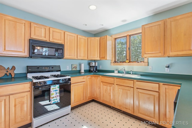 kitchen featuring light brown cabinetry, gas stove, black microwave, and a sink