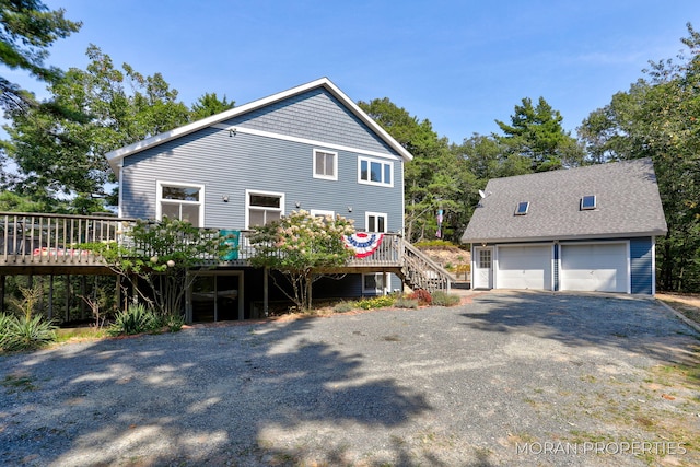 view of front facade featuring an outbuilding, stairway, a shingled roof, a garage, and a deck