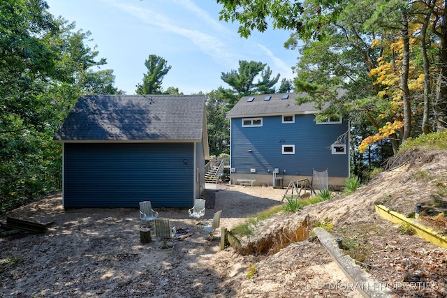 rear view of house with central air condition unit, roof with shingles, and stairway