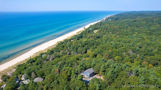 drone / aerial view featuring a beach view, a forest view, and a water view