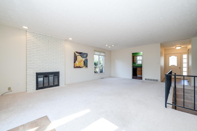 carpeted living room featuring a brick fireplace, recessed lighting, and visible vents