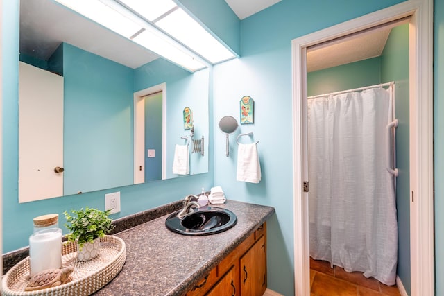 bathroom featuring a shower with shower curtain, double vanity, a skylight, and a sink