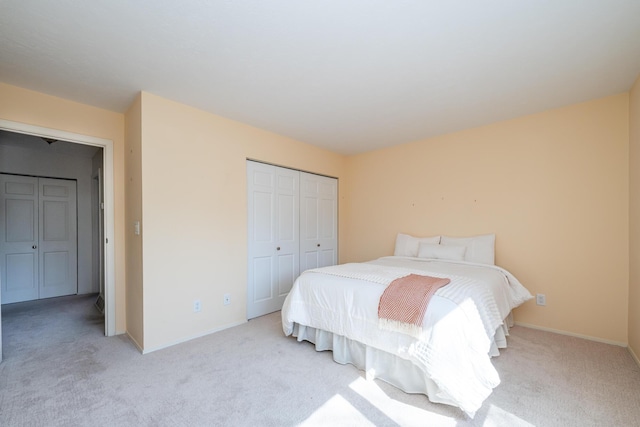 bedroom featuring light carpet, baseboards, and a closet