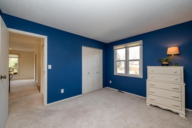 carpeted bedroom featuring a closet, visible vents, multiple windows, and baseboards