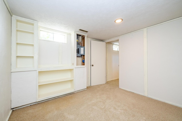 below grade area with electric panel, visible vents, carpet, and a textured ceiling