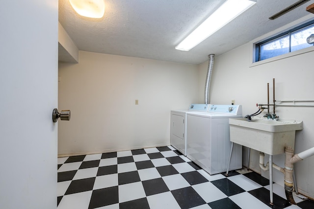 washroom with a textured ceiling, tile patterned floors, visible vents, and washing machine and clothes dryer