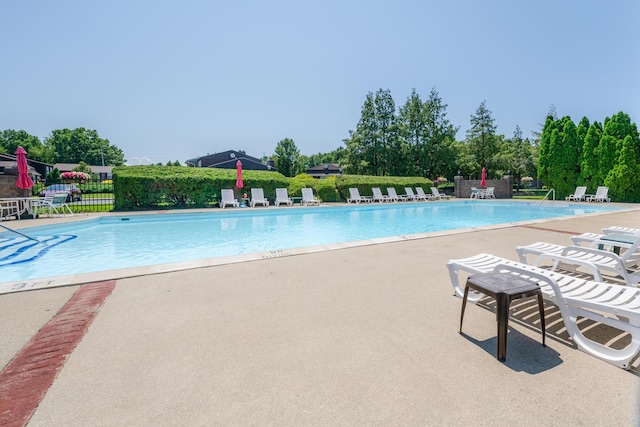 community pool with a patio area and fence