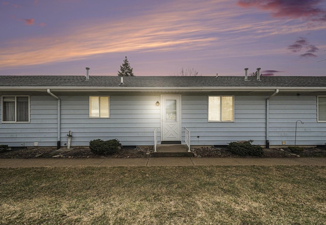 back of house with a lawn and roof with shingles