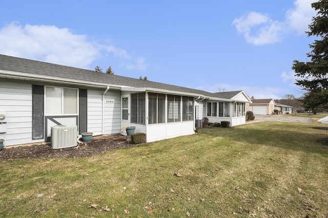 back of house with central air condition unit, a yard, and a sunroom