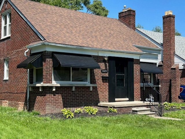 view of front of home featuring a chimney, brick siding, and a shingled roof