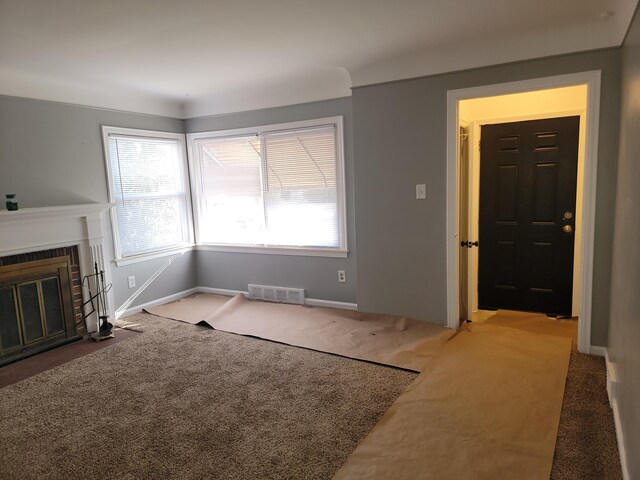 unfurnished living room featuring visible vents, carpet flooring, baseboards, and a fireplace with flush hearth