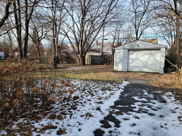 yard covered in snow featuring an outbuilding, fence, and a garage