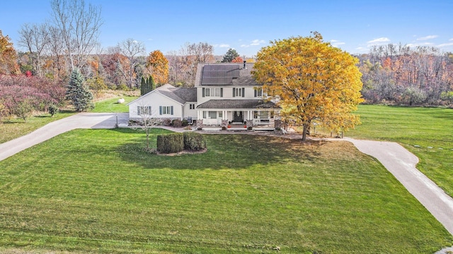 view of front of property with solar panels and a front lawn