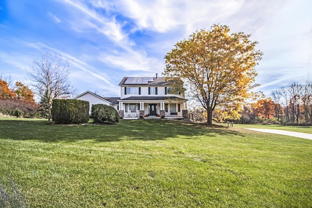 view of front of property with roof mounted solar panels, a porch, and a front yard