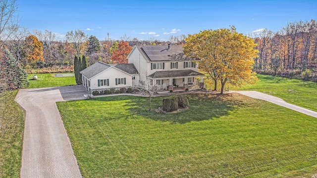 view of front of property featuring a wooded view, driveway, and a front yard