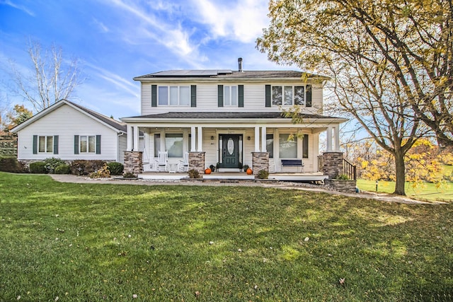 view of front of house featuring roof mounted solar panels, a porch, and a front yard