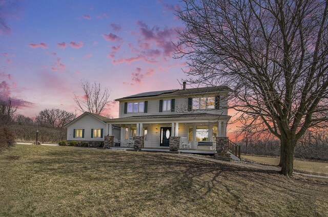 view of front of property with solar panels, a porch, and a front lawn