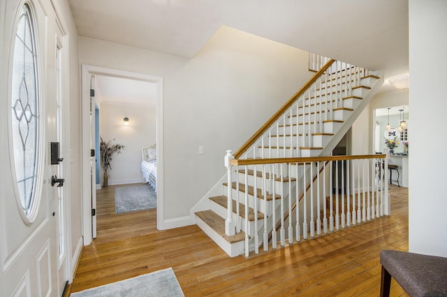 foyer featuring a wealth of natural light, stairway, baseboards, and wood finished floors