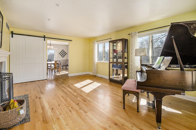 sitting room featuring visible vents, baseboards, light wood-style flooring, and a barn door