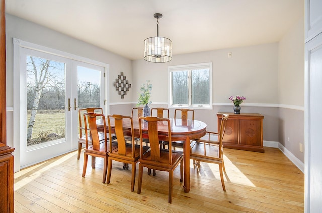 dining area featuring french doors, baseboards, light wood-style floors, and a notable chandelier