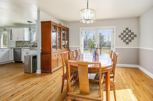 dining room featuring a healthy amount of sunlight, light wood-type flooring, and a chandelier