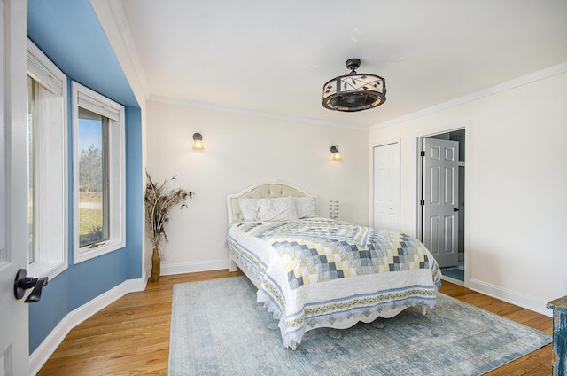 bedroom featuring light wood finished floors, baseboards, and ornamental molding