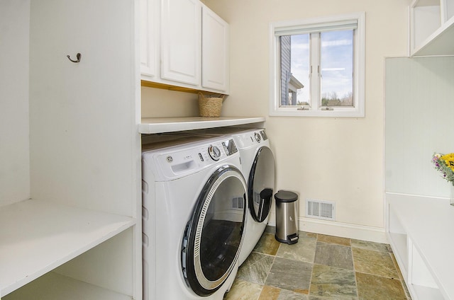 laundry room with visible vents, independent washer and dryer, stone finish floor, cabinet space, and baseboards