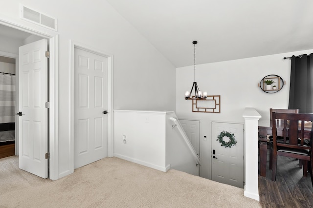 entryway featuring a notable chandelier, visible vents, lofted ceiling, and carpet floors